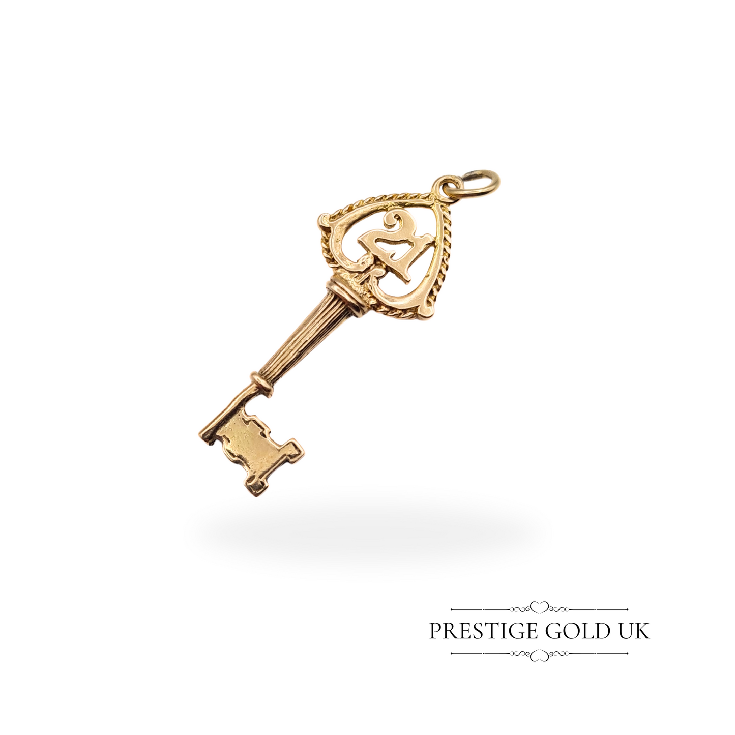 A close-up view of a vintage 9ct gold key charm featuring the number "21" in ornate design, hallmark from Birmingham 1968, ideal as a 21st birthday gift.