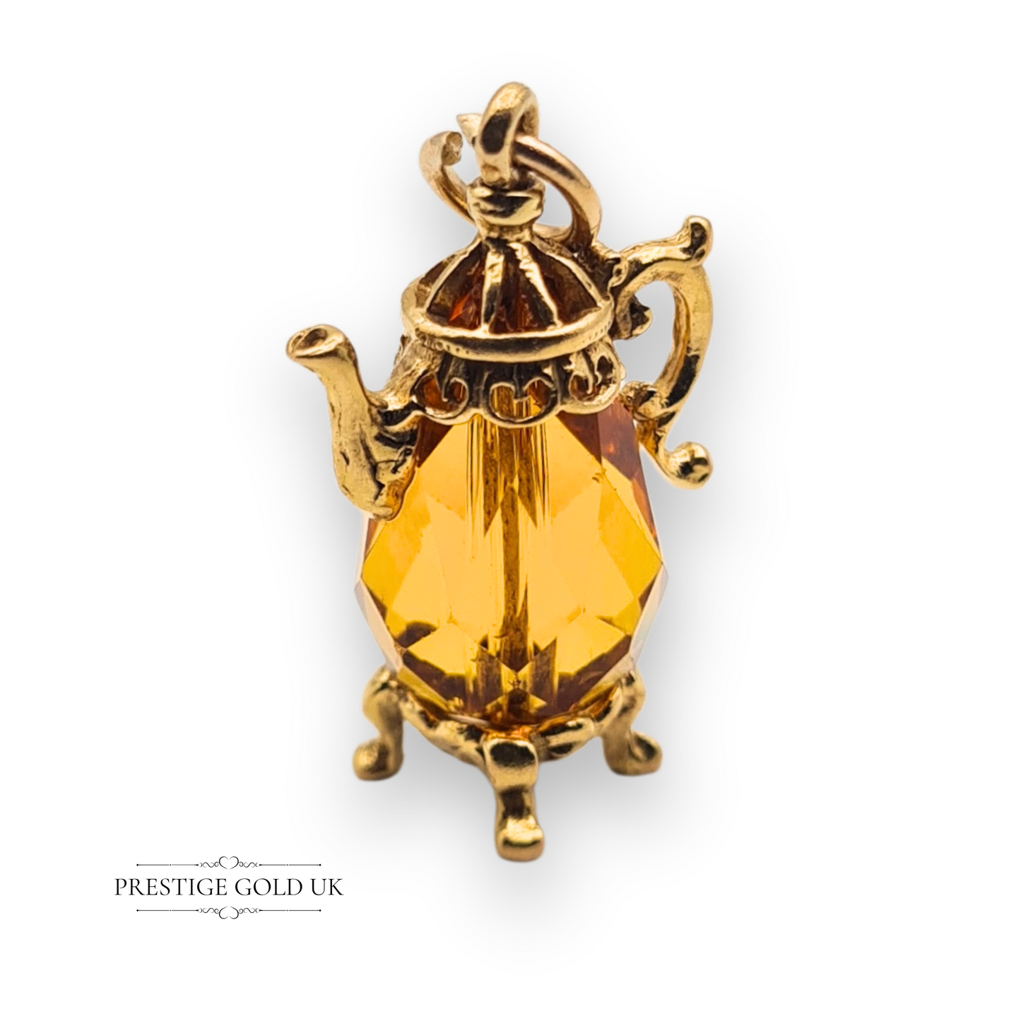 Close-up of a 9ct gold vintage teapot charm with a faceted orange gem centre, ornate spout and handles, fully hallmarked London 1975, novelty collectible.
