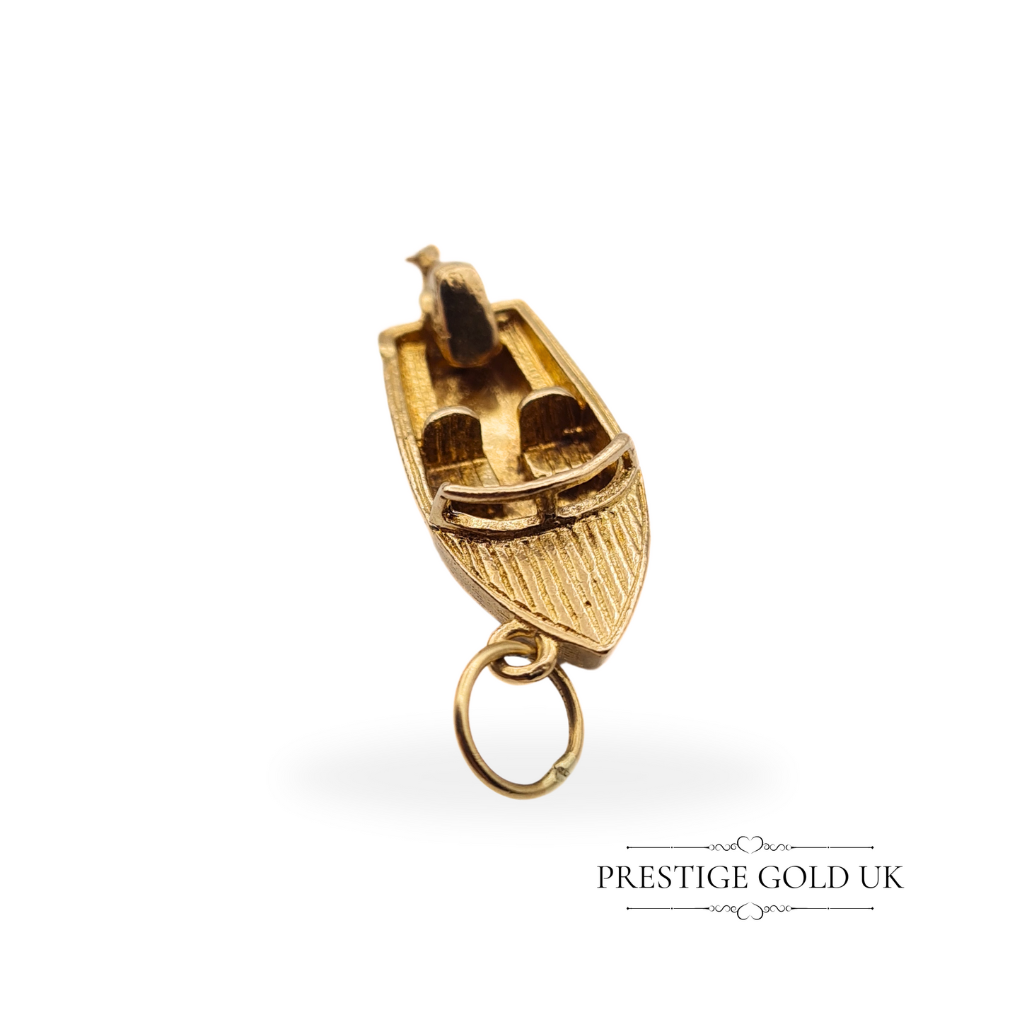 Close-up of a vintage 9ct gold motorboat charm with intricate wood-style detailing and a moving outboard motor, fully hallmarked London 1971.