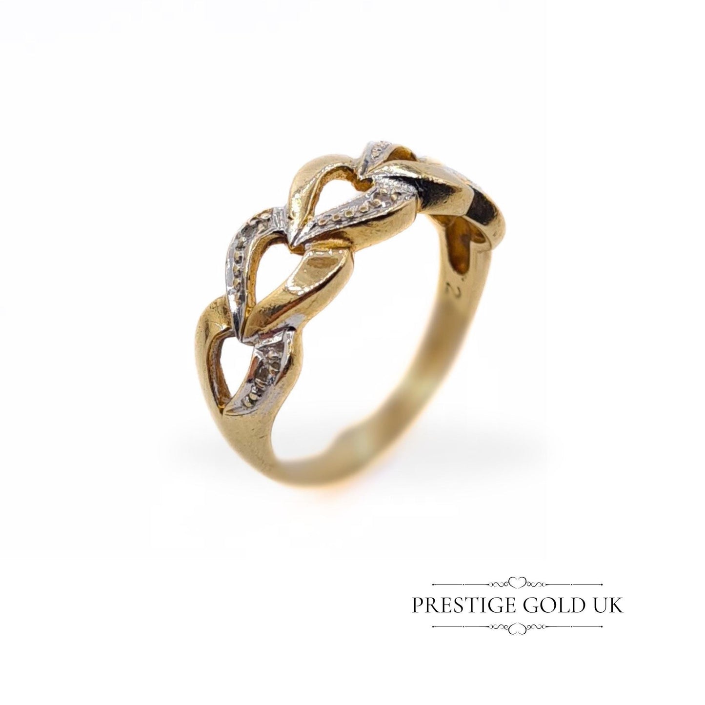 A 1993 British-hallmarked 9ct white and yellow gold ring with interlocking diamond-set hearts and a tapered band, ideal for jewellery lovers and collectors of romantic designs.