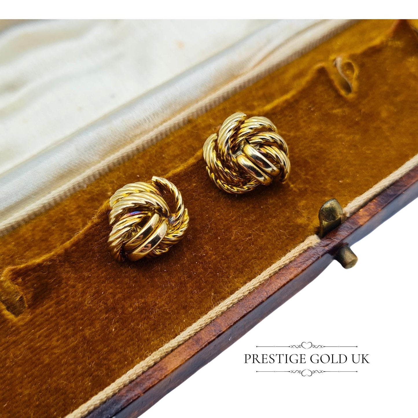 A pair of 9ct gold twisted knot earrings displayed on a vintage brown jewellery box, highlighting their elegant charm.