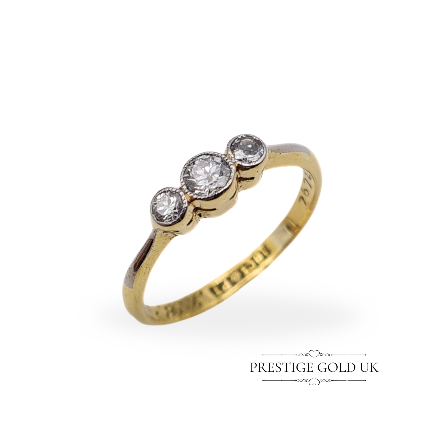 Close-up of an antique 18ct gold and platinum triple diamond ring, featuring a beautifully engraved band with vintage initials.
