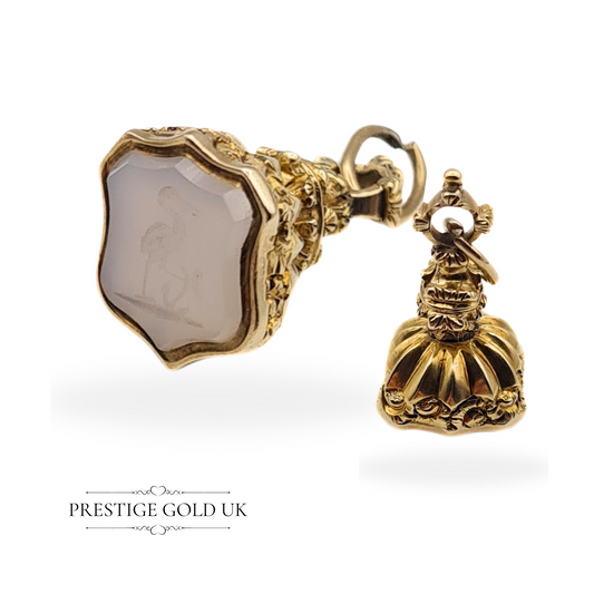 Antique 9ct gold fob pendant with ornate Victorian-style detailing and a stork and anchor crest engraved in the stone, shown close-up against a white background.