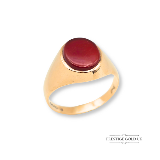 A tiny vintage 9ct gold pinky ring set with an oval red-orange carnelian gemstone in a classic signet style, fully hallmarked London 1975, ideal for retro jewellery lovers and suitable for stacking or wearing alone.