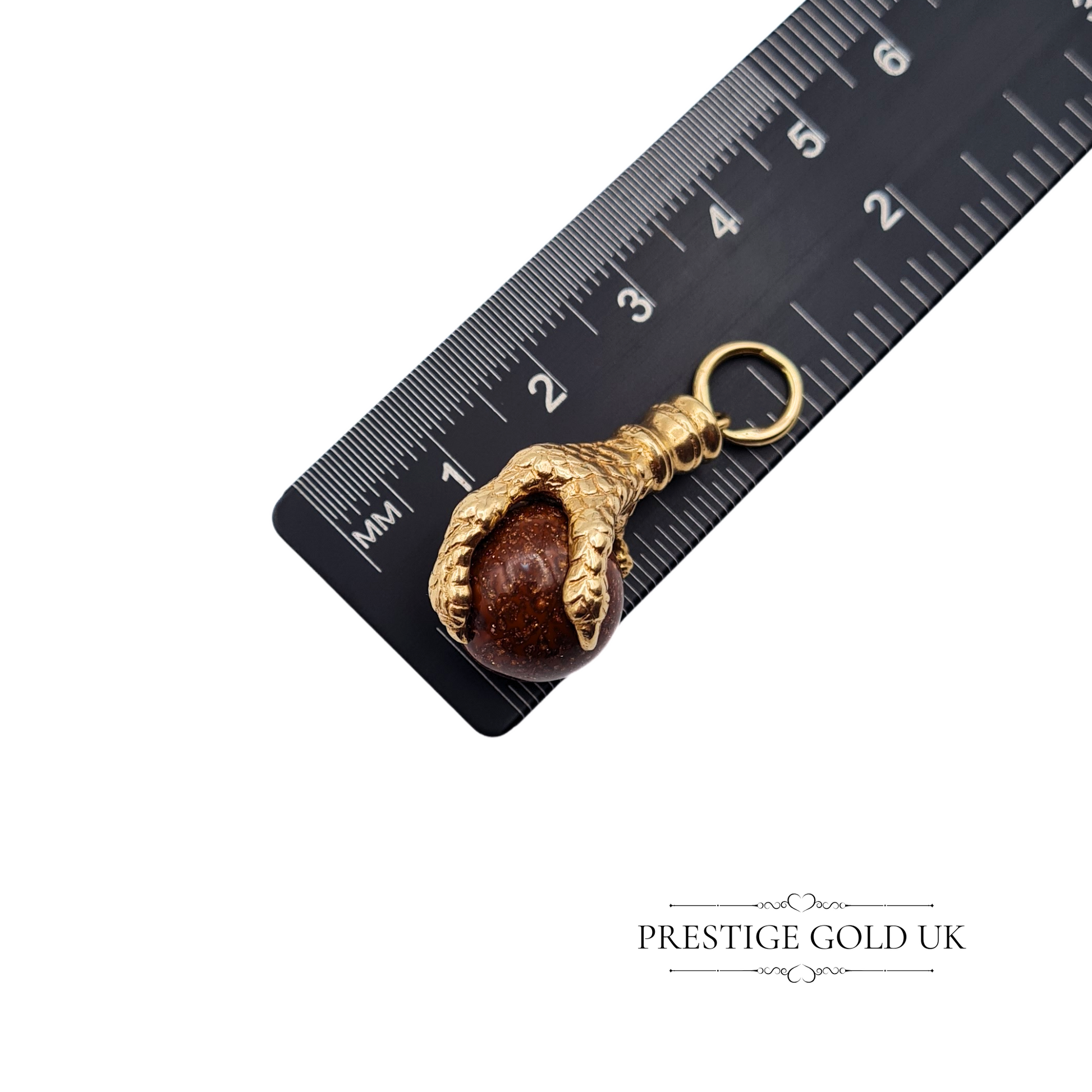 Gold claw charm placed on a ruler, showing its 29mm height and substantial size.