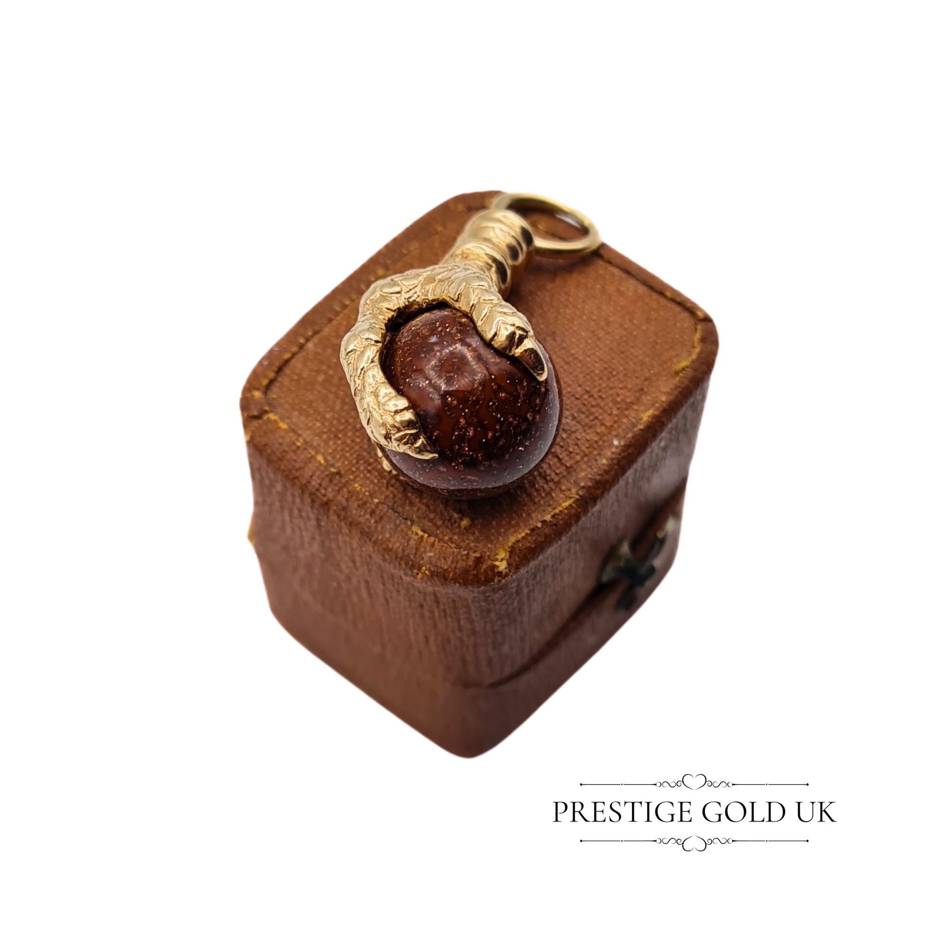Ornate gold claw pendant displayed on a brown vintage jewellery box, showcasing its heavyweight design.