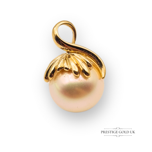 Close-up of an 18ct gold pendant featuring a creamy cultured pearl with a scalloped gold cap and tested gold loop, classic drop design, 15mm in size.
