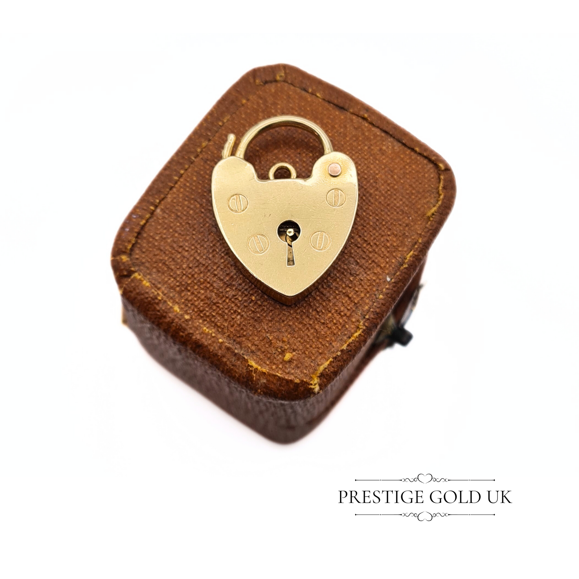 Close-up of a vintage 9ct gold heart-shaped padlock charm, hallmarked London 1976, with LC maker’s mark, displayed on a vintage jewellery box.