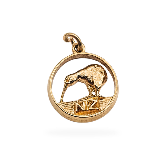 9ct gold NZ kiwi charm pendant, stamped 9ct and fully tested, measuring 13mm wide and 2mm deep, featuring a detailed New Zealand kiwi bird within a circular frame above raised NZ lettering. Lightweight 1.3g souvenir design in good pre-owned condition.