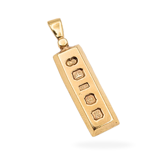 Solid 9ct gold ingot pendant fully hallmarked for Birmingham 1984 with LW maker’s mark. Rectangular gold bar pendant measuring 30mm by 7mm by 2mm and weighing 4.15g, featuring crown, 375, anchor, and date letter K hallmarks.