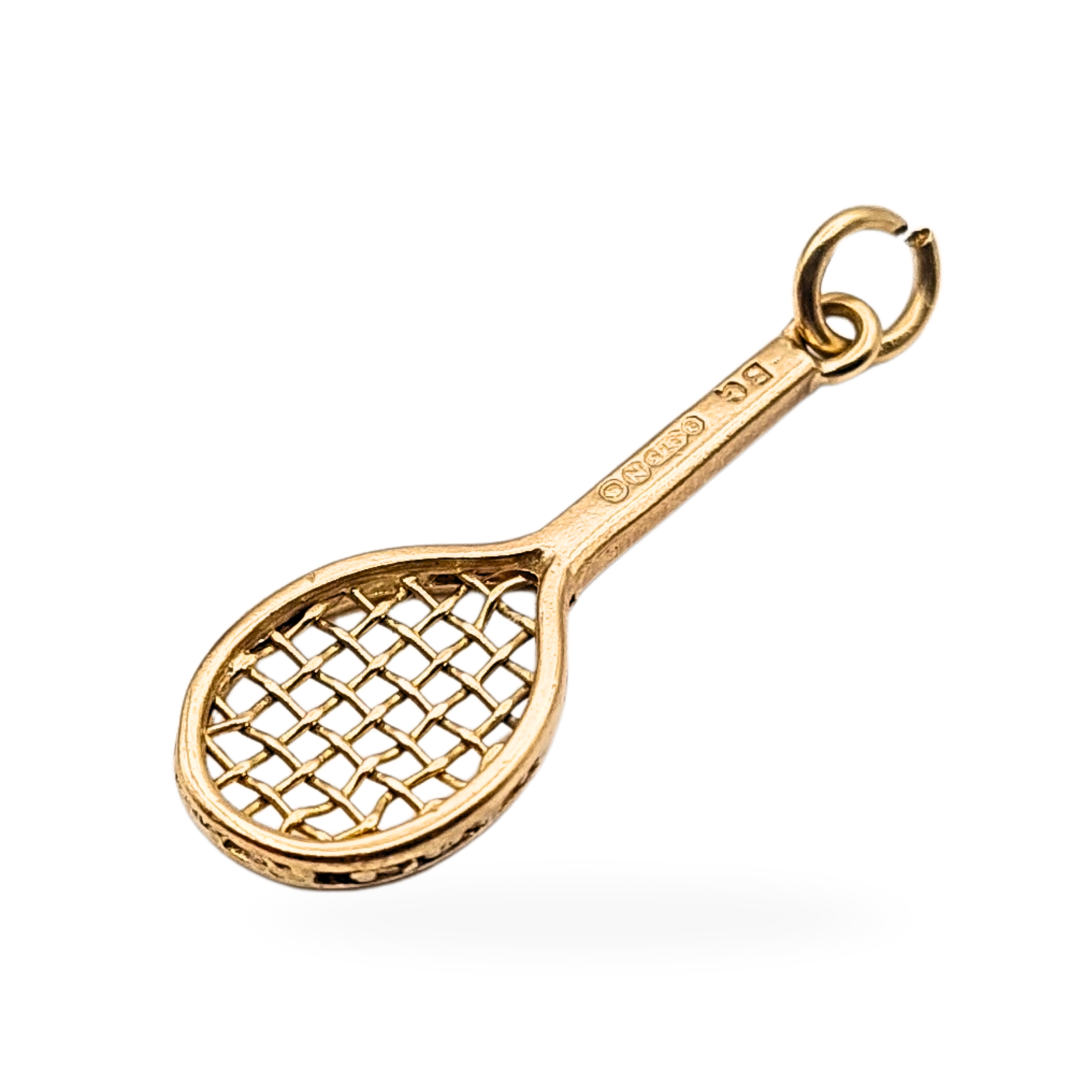 Photograph of a 9ct gold racket charm hallmarked London 1949, 22mm long by 7mm wide, featuring intricate openwork string detailing and a solid handle. Ideal as a gold tennis, squash, or badminton pendant or collector’s charm.