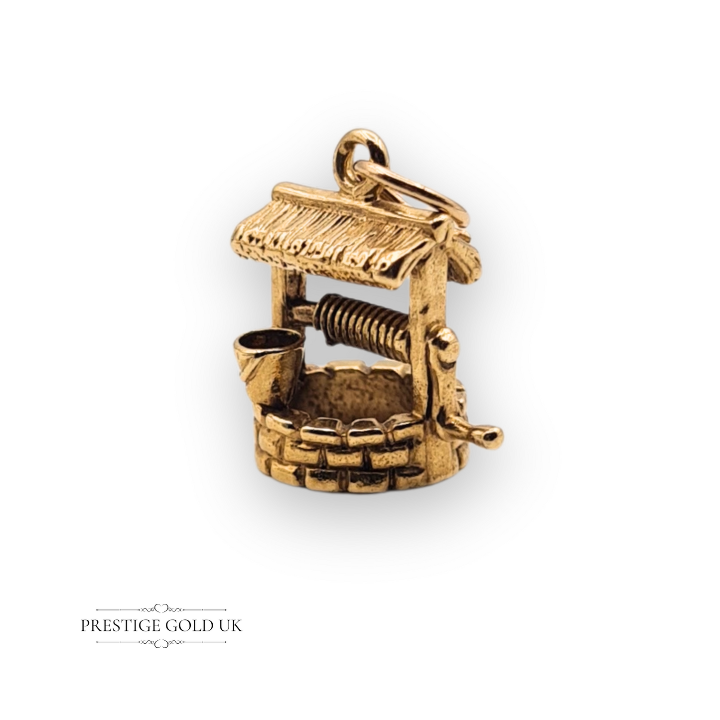 Detailed 9ct gold wishing well charm pendant with miniature bucket and crank, hallmarked Birmingham 1975, vintage jewellery design with textured detailing.
