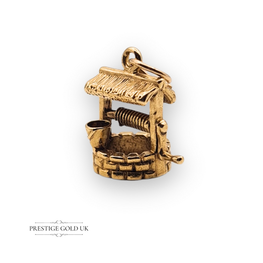 Detailed 9ct gold wishing well charm pendant with miniature bucket and crank, hallmarked Birmingham 1975, vintage jewellery design with textured detailing.

