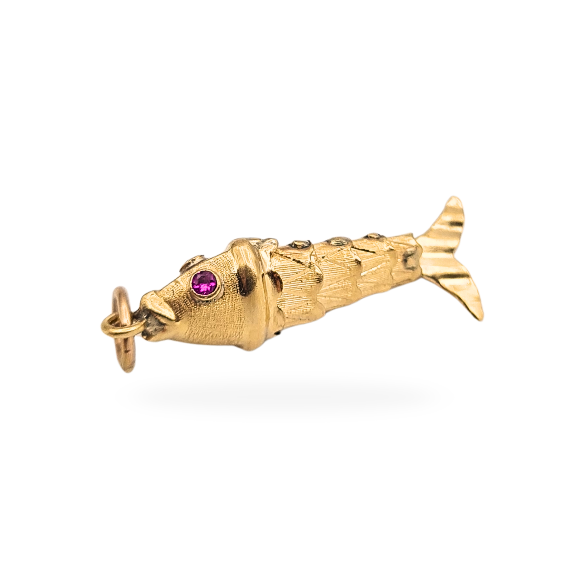 Vintage articulated 9ct gold fish charm measuring 24mm long and weighing 0.97g, with moving body segments and textured scale detail. Set with pink stone eyes and polished striped tail, not hallmarked but fully tested as 9ct gold.