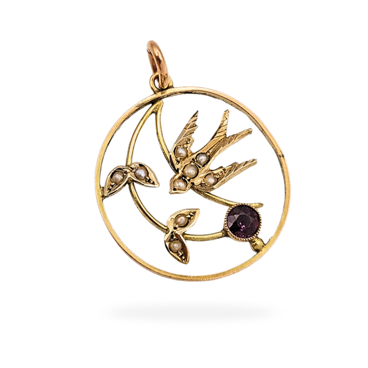 Antique 9ct gold swallow pendant stamped and fully tested, measuring 24mm and weighing 1.51g. Circular gold frame featuring a detailed swallow motif set with seed pearls and a central garnet, photographed front and back to show condition and craftsmanship.