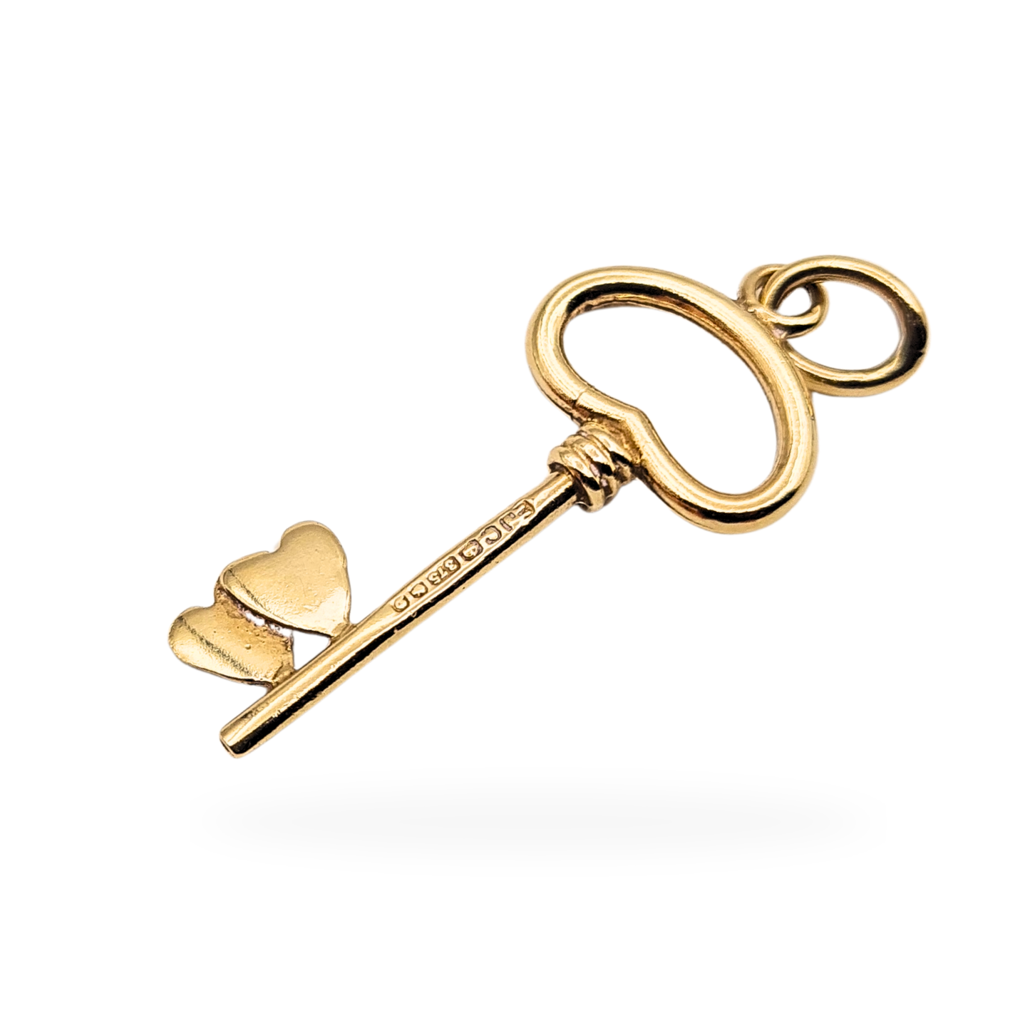 9ct yellow gold heart key charm fully British hallmarked, measuring 25mm long and weighing 0.9g. Featuring an open heart shaped bow and twin heart detail at the key bit, polished finish, suitable as a small pendant or charm bracelet addition.
