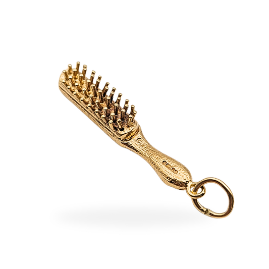 9ct yellow gold hair brush charm pendant, hallmarked London 1977, weighing 6.53 grams and measuring 41mm by 8mm. Realistic brush detail with textured handle, perfect gift for a hairdresser or collector, solid gold and fully hallmarked.