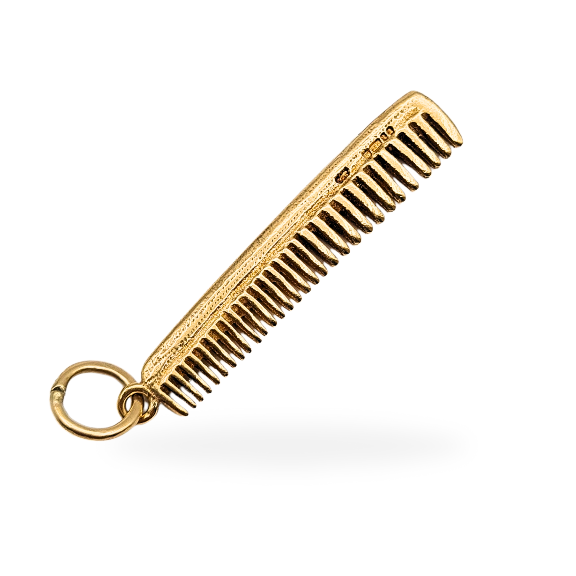 9ct yellow gold comb pendant weighing 4.10 grams, fully hallmarked London 1977. Solid gold with detailed textured finish and fine comb teeth, measuring 42mm by 8mm by 2mm. Ideal hairdresser or barber gift, vintage collectible pendant.