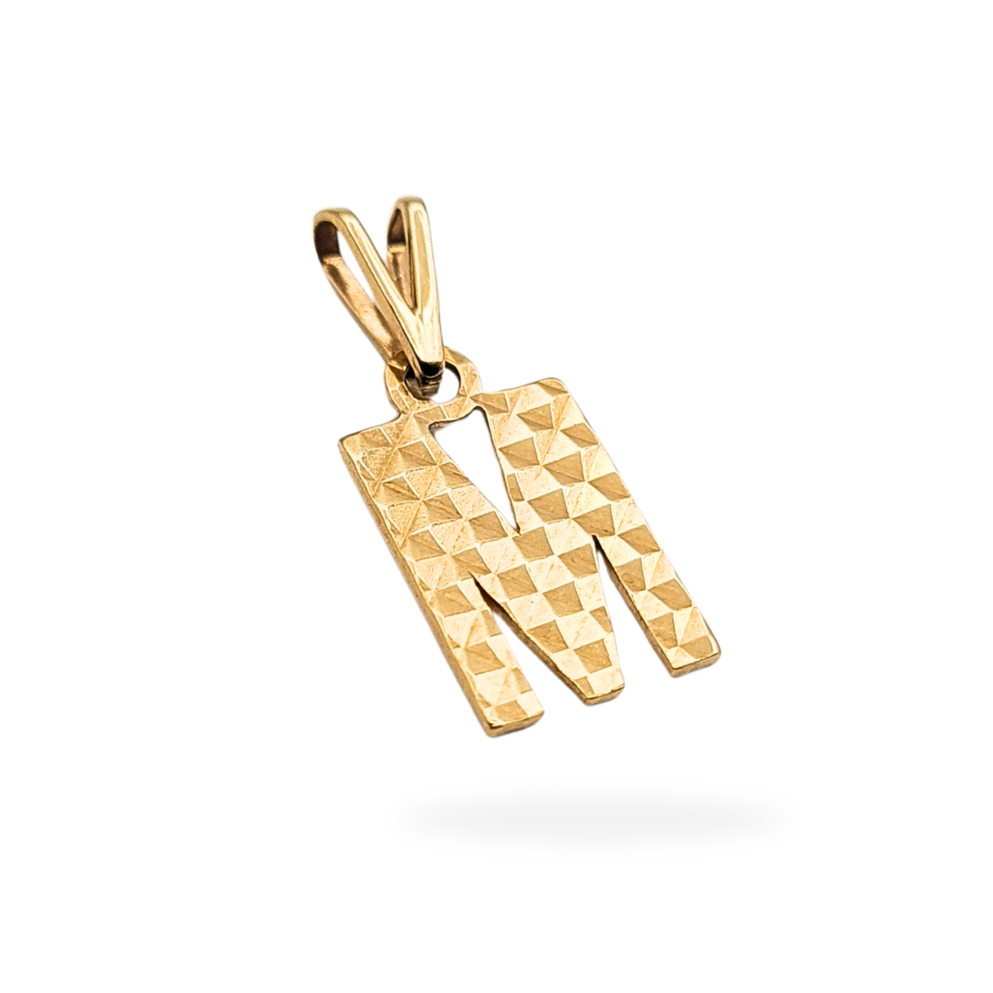 Solid 9ct gold letter M pendant with faceted waffle texture on the front and smooth polished back. Fully British hallmarked. Measures 13mm tall by 7mm wide. Lightweight solid gold initial charm for everyday wear or gifting.