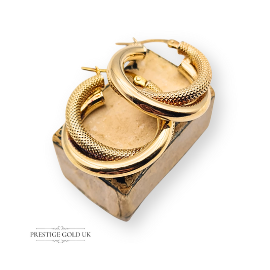 Close-up of 9ct two tone gold interlocking hoop earrings with flip top closure, featuring a smooth and textured finish in yellow and white gold. Lightweight, hollow design with round shape and Birmingham hallmark, 20mm diameter.