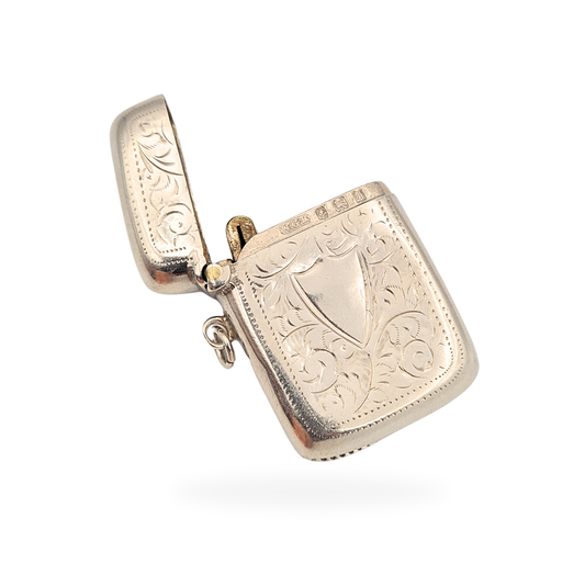 Antique sterling silver vesta case with curved rectangular form and hand-engraved scrollwork. Birmingham hallmarked 1907, measuring 4cm tall with hinged lid, striker base and side loop. Edwardian pocket match safe in fair antique condition.
