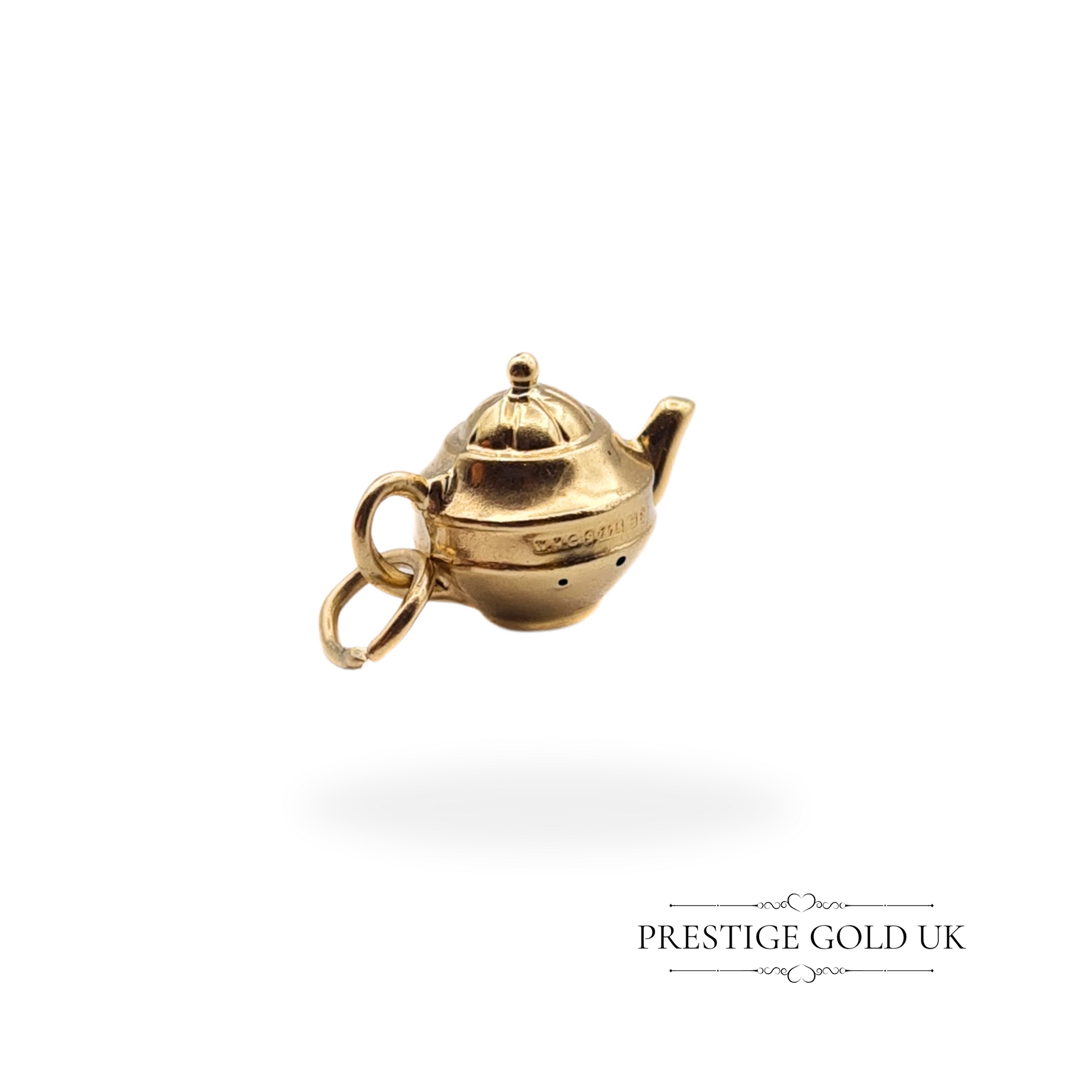 A close-up view of a vintage 9ct gold teapot charm, hollow design with intricate details, fully hallmarked Birmingham 1990.
