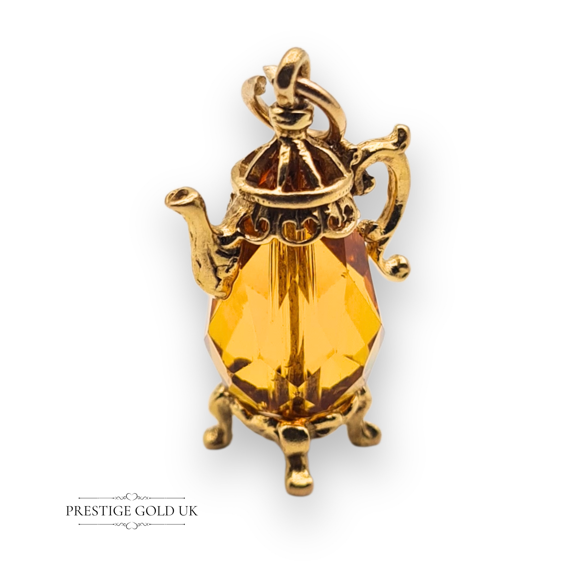 Close-up of a 9ct gold vintage teapot charm with a faceted orange gem centre, ornate spout and handles, fully hallmarked London 1975, novelty collectible.
