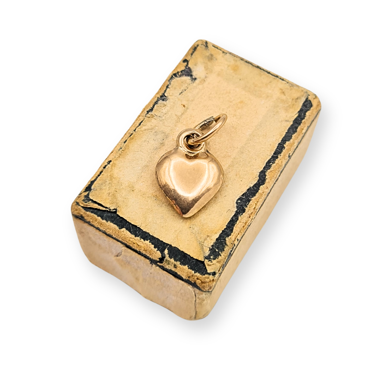 Small 9ct gold puffy heart charm pendant measuring approximately 11mm tall and 8mm wide with polished finish and hollow construction. Fully tested gold charm shown beside ruler and on fingertip for scale, a delicate miniature heart pendant suitable for necklace or bracelet.