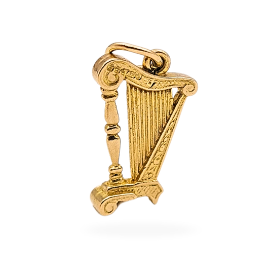 Photograph of a small 9ct gold harp charm, 18mm tall including bail and 11mm wide, featuring detailed string and scroll design. The jump ring is stamped 9ct. Ideal as a gold musical instrument pendant or collector’s charm.
