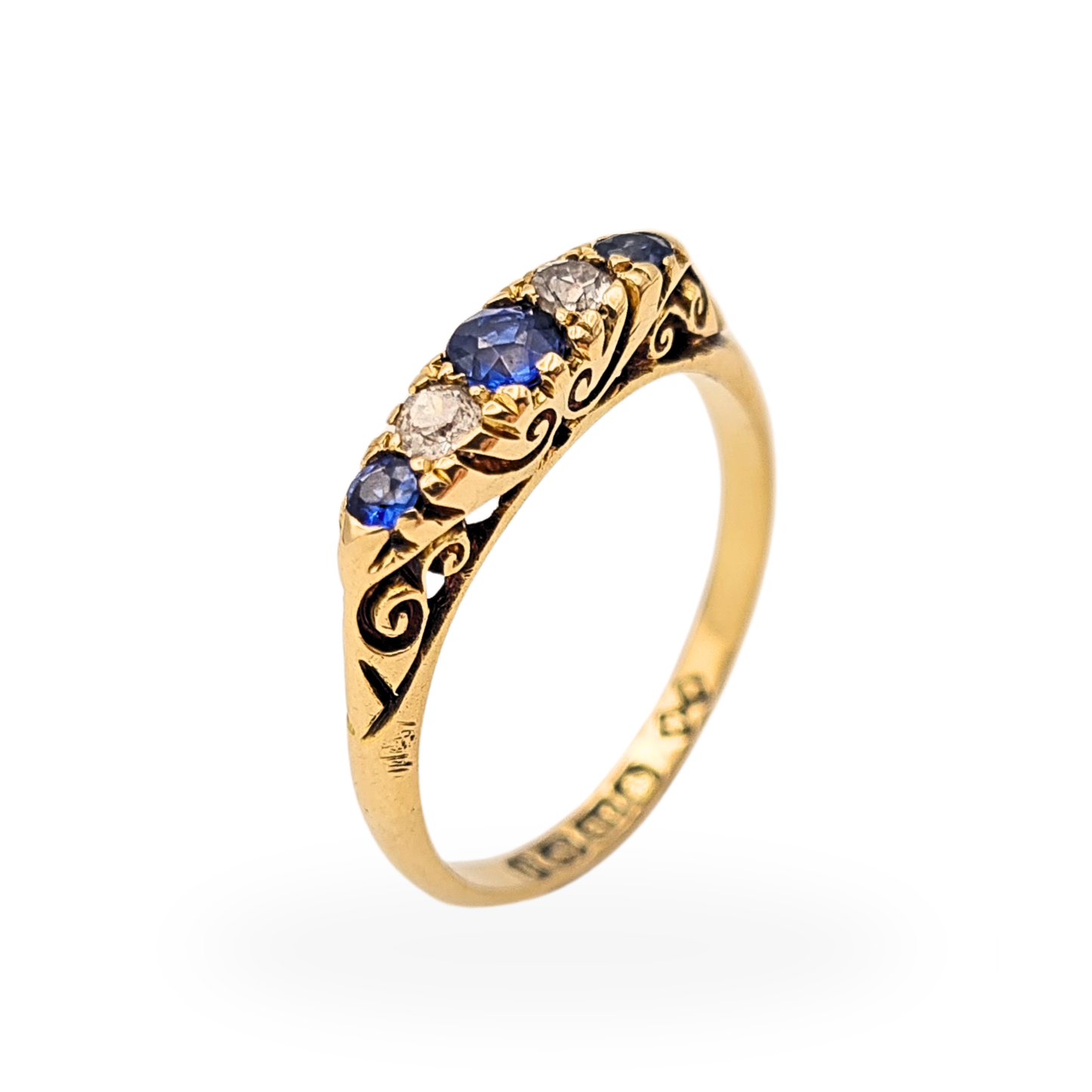 18ct gold antique ring with alternating blue sapphires and diamonds in a five stone setting, approx 4mm wide band with ornate engraved scroll shoulders, Birmingham 1915 hallmark visible, classic Edwardian era style fine jewellery piece