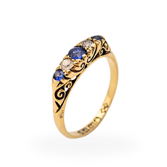 18ct gold antique ring with alternating blue sapphires and diamonds in a five stone setting, approx 4mm wide band with ornate engraved scroll shoulders, Birmingham 1915 hallmark visible, classic Edwardian era style fine jewellery piece