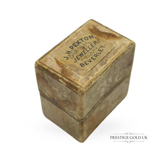 A rare antique paper ring box from J.H. Pexton Jeweller, Beverley, measuring 25mm x 17mm x 27mm. Featuring a faded beige marbled exterior with an aged patina and a rich burgundy velvet interior, this unique collectible is ideal for vintage jewellery enthusiasts and collectors.