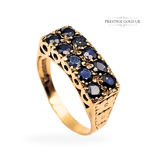 Vintage 9ct yellow gold twin row sapphire ring, fully hallmarked Birmingham 1977. Features ten dark blue sapphires in an ornate floral claw setting with engraved sides. Size UK T / US 9 3/4, wide 18 x 7mm ring face, weight 5.04g, polished finish.