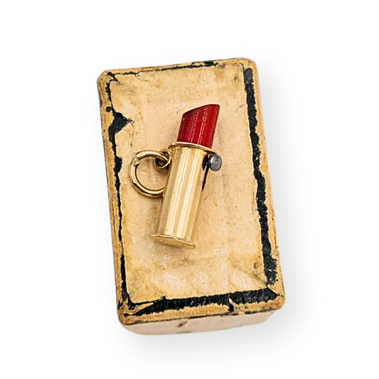 Photograph of a miniature 9ct gold lipstick charm with moving parts, showing full British hallmarks. The charm measures 14mm long by 5mm wide and weighs 0.75g. A detailed close-up of the red enamel lipstick in solid gold casing, rare vintage piece.