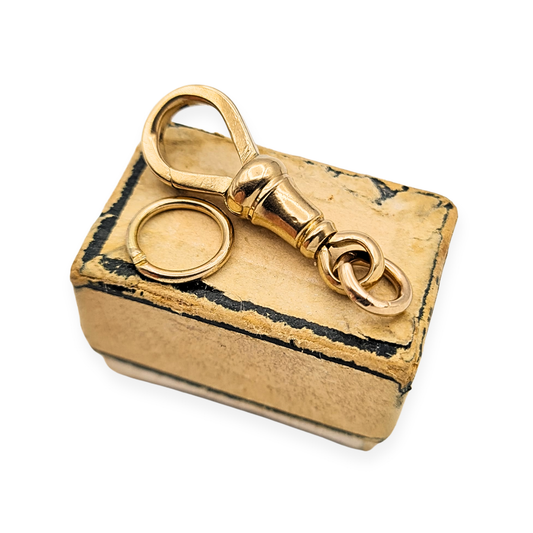 Close-up of a 9ct yellow gold Albert chain dog clip with swivel fitting, flat square section and stamped 375 mark. Vintage pocket watch or fob clip with 25mm length and jump rings (9mm and 7mm). Weight 2.99g, excellent condition.