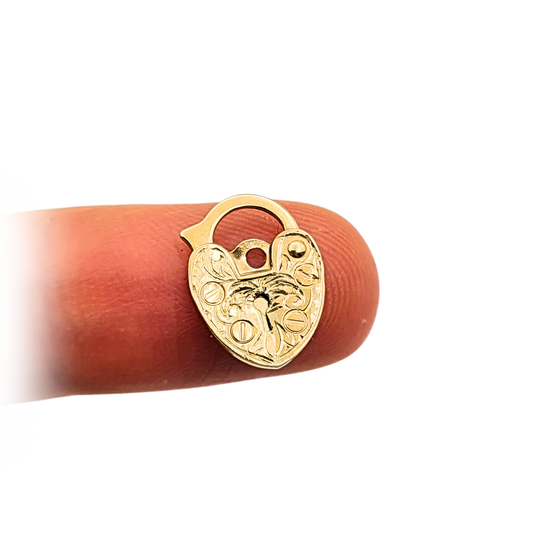 Tiny 9ct yellow gold heart-shaped padlock, hallmarked London 1989, weighing 0.49g and measuring 13x11x1.5mm. Hand engraved with scroll detailing, slightly flattened with age. Ideal for use as a gold bracelet clasp or pendant charm.