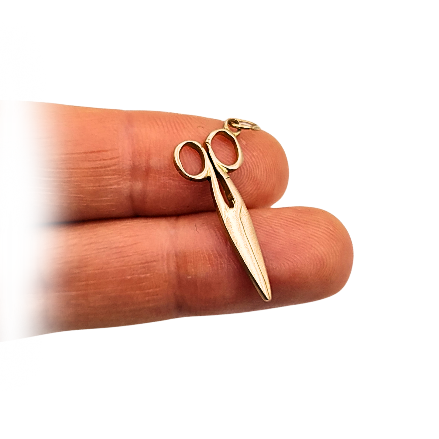 Photograph of a 9ct solid gold scissors charm, 25mm long and 10mm wide, stamped 9ct on the handle. Weighing 1.13 grams, this charm features openwork handles and a smooth polished finish, ideal as a gold seamstress or tailor pendant.