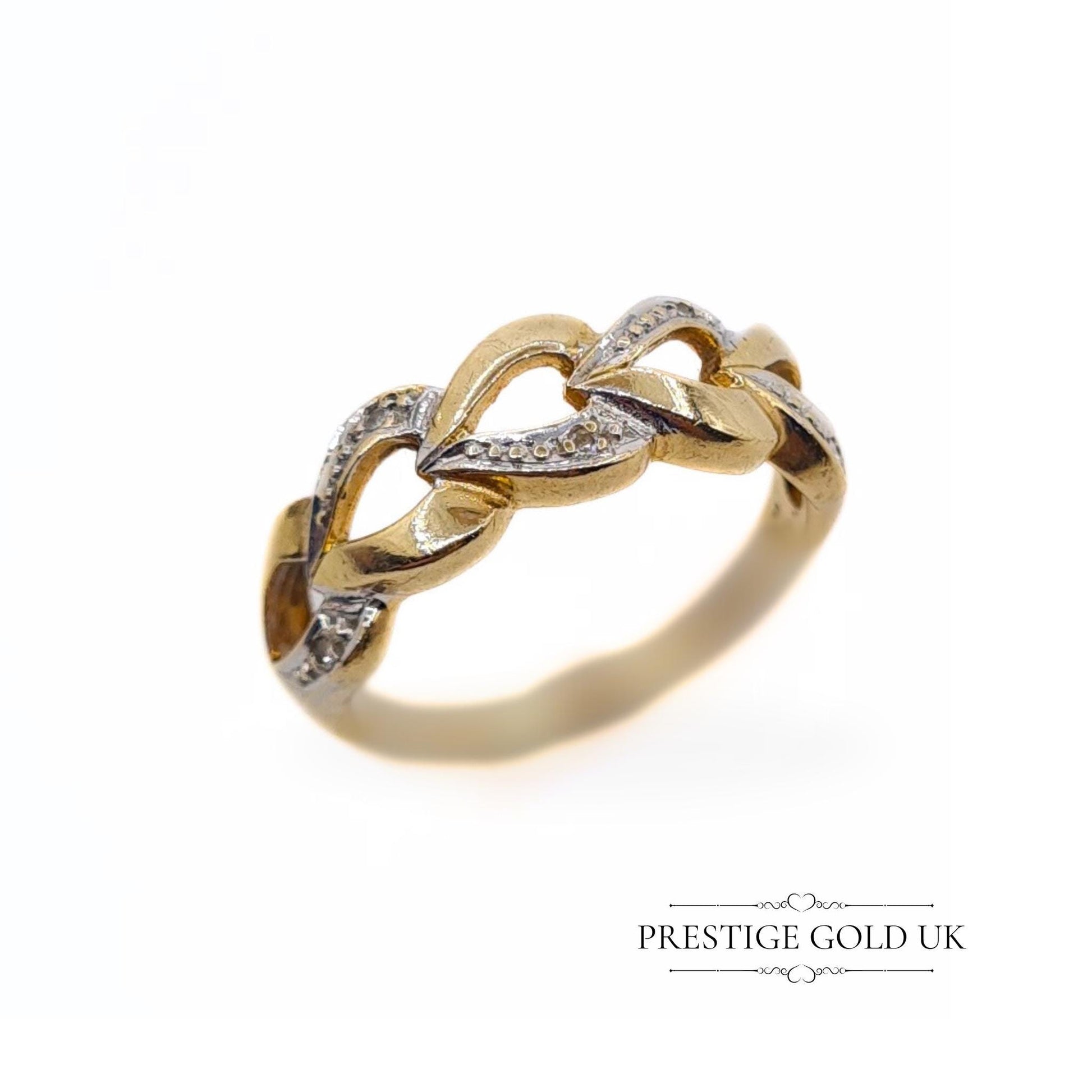 A 1993 British-hallmarked 9ct white and yellow gold ring with interlocking diamond-set hearts and a tapered band, ideal for jewellery lovers and collectors of romantic designs.
