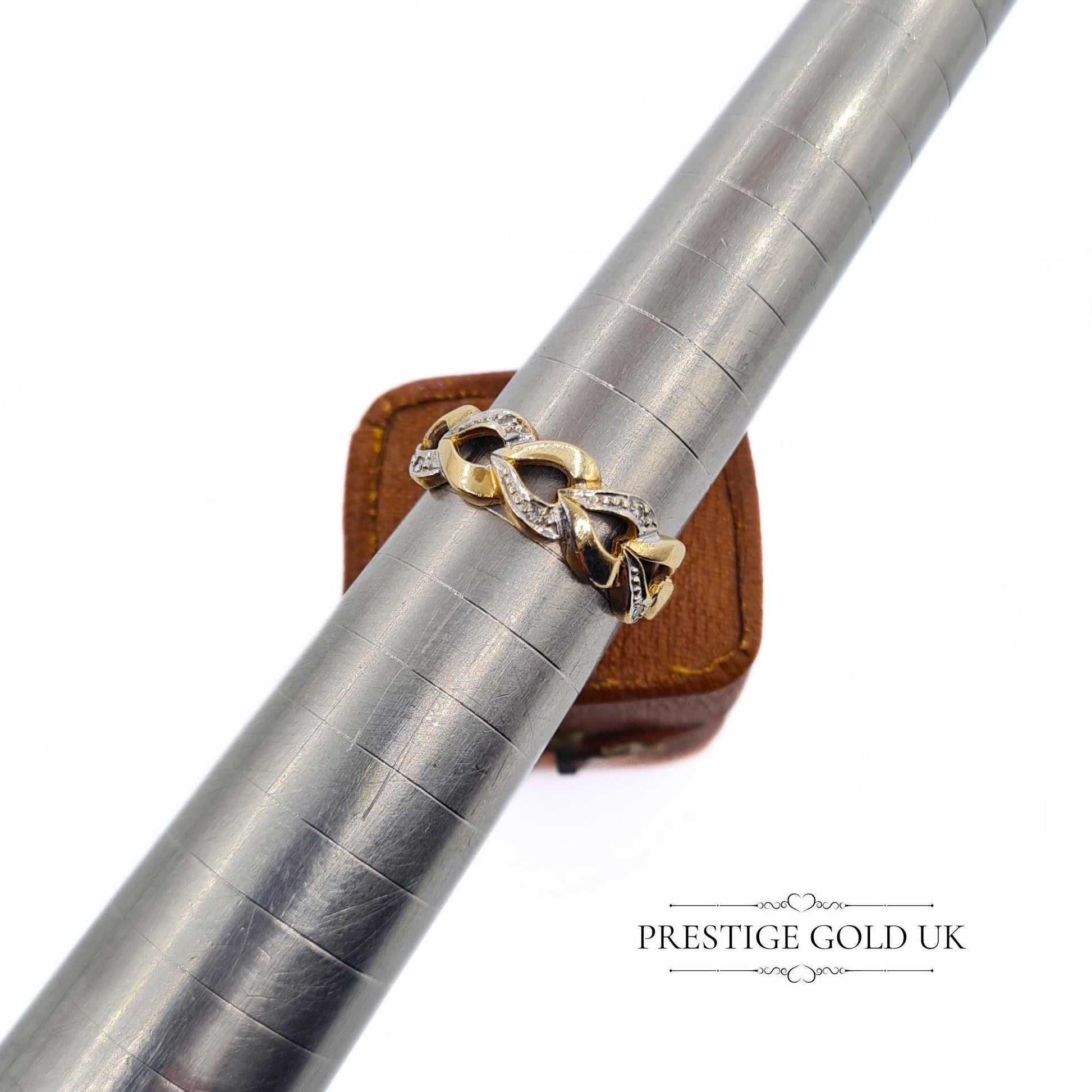 A 1993 British-hallmarked 9ct white and yellow gold ring with interlocking diamond-set hearts and a tapered band, ideal for jewellery lovers and collectors of romantic designs.