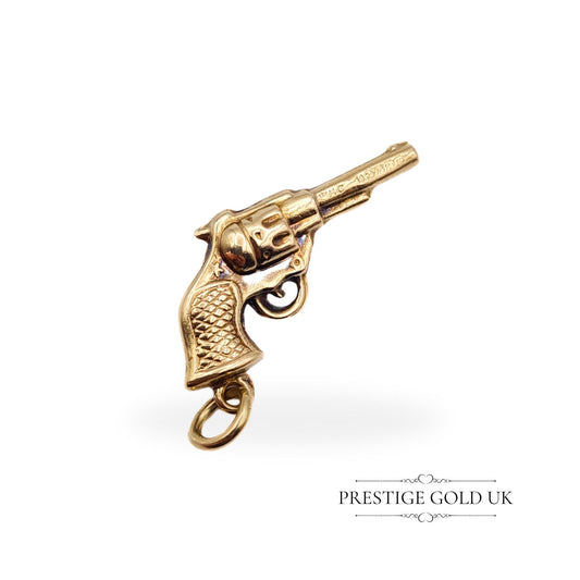 A small 9ct gold revolver hand gun charm, measuring 20mm in length, featuring detailed craftsmanship and a hollow construction. Fully British hallmarked, ideal for a unique pendant or charm.