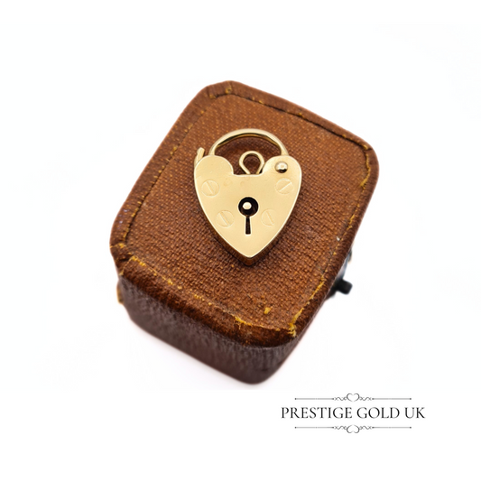 Artistic presentation of the heart-shaped gold padlock charm on a vintage-style jewellery box.